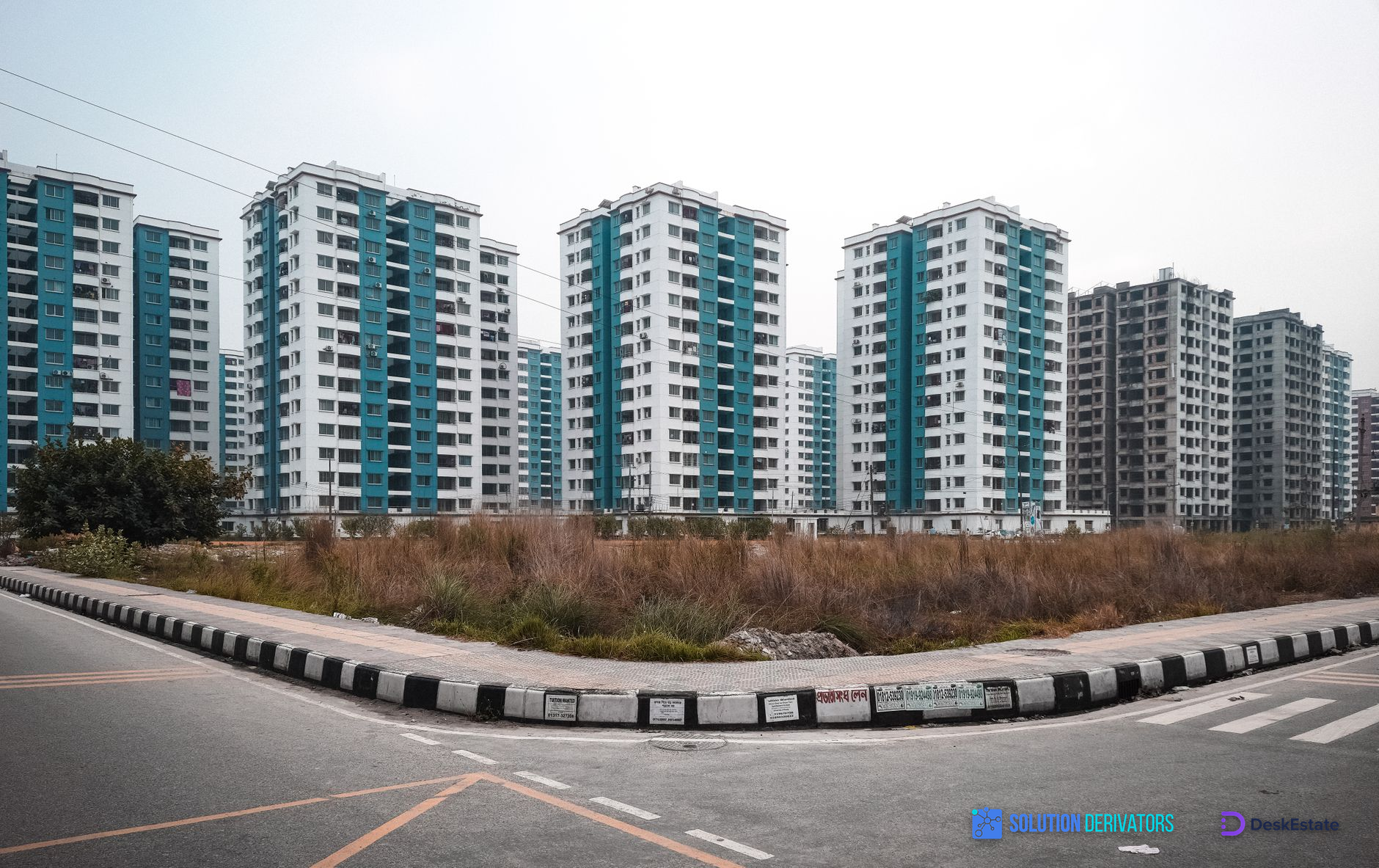 Contemporary apartment buildings in Dhaka, Bangladesh, captured against a white sky.